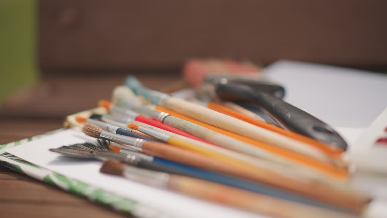 Watercolors and brushes outdoors. Bright watercolor set with brushes resting on bench outdoors. Casual painting setup featuring vibrant watercolor paints and sketchbook in sunlight