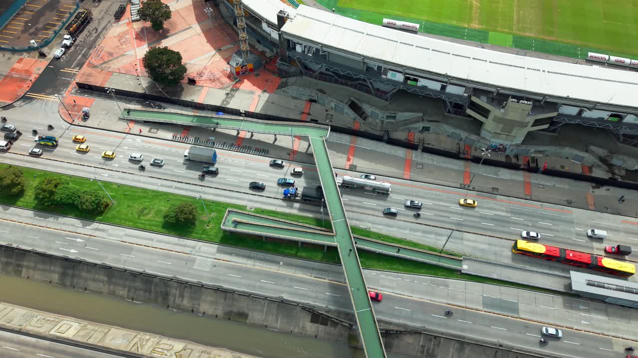 Air orbit establishing with little traffic on Avenida NQS in Bogota, Colombia with pedestrian overpasses, sunny day.