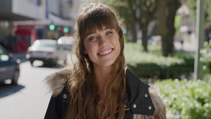 ritratto di una bella giovane donna sorridente allegra che si gode di una giornata urbana soleggiata con un aspetto positivo sullo sfondo della strada della città in rallentatore