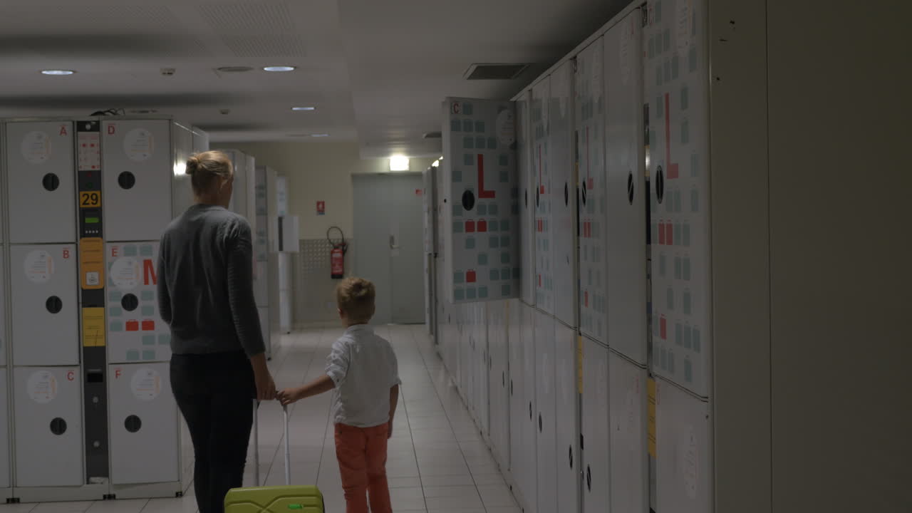 Mother and child leaving suitcase in baggage room