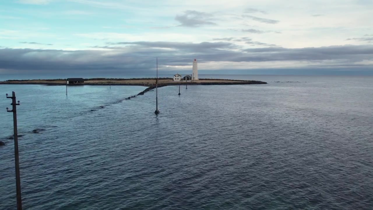 Dramatisk flygvy över det ikoniska fyren Grotta. Detta fridfulla havslandskap fångar Reykjaviks halvö under en mulen himmel.