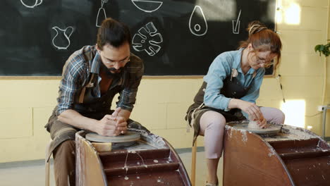 two people working on pottery wheels