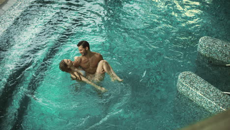 Top-view-of-happy-couple-enjoying-pool.-Joyful-couple-relaxing-at-wellness-hotel