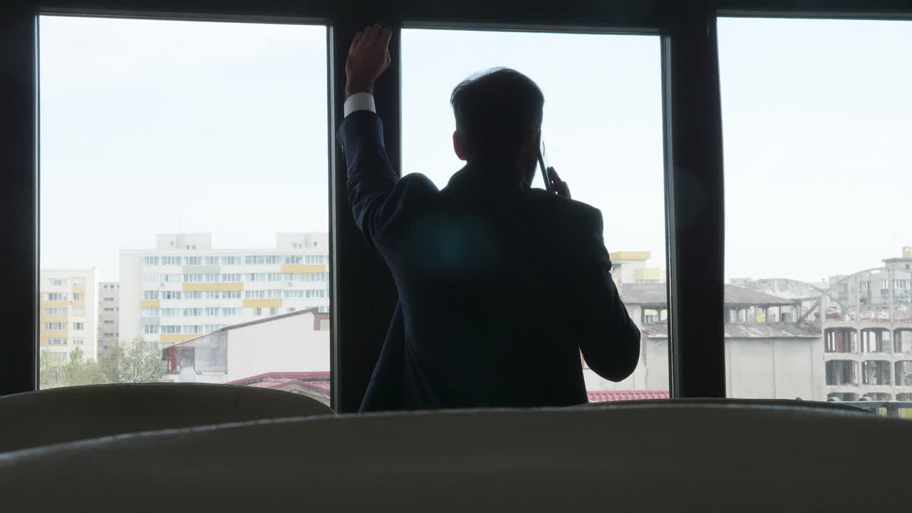Man talking on phone looking out of office window