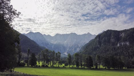 kamnik savinja alps from jezersko, slovenia, timelapse of clouds above mountains and meadows with trees in front