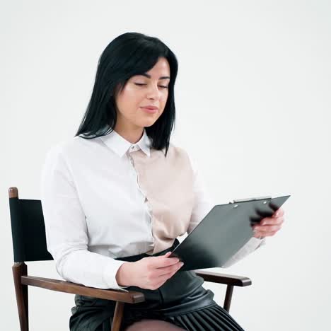 portrait of a beautiful woman reading. attractive brunette girl holding a folder and looking at the document on white studio background.