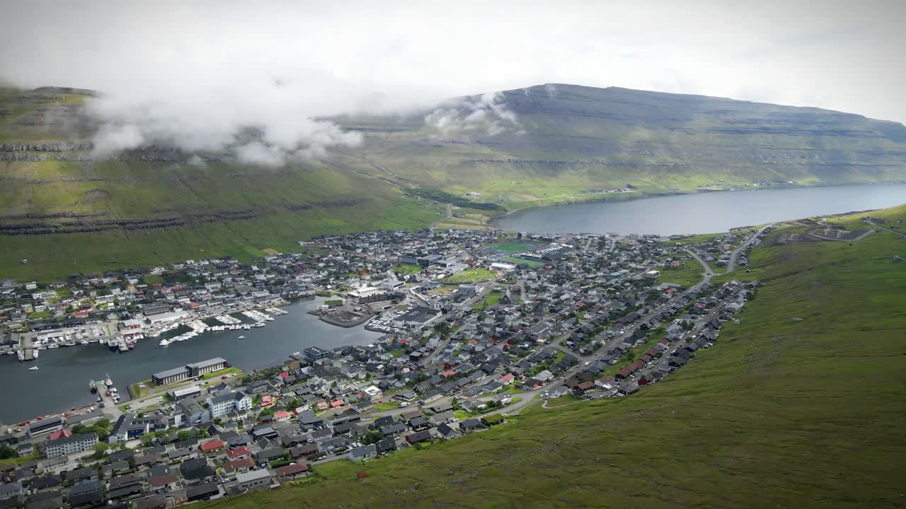 페로 제도 (faroe islands) 의 클라크스비크 (klaksvik) 의 공중 풍경, 그림 같은 항구, 다채로운 마을, 그리고 극적인 산 풍경. 도시 매력과 자연의 아름다움이 혼합되어 평온한 분위기를 만니다.