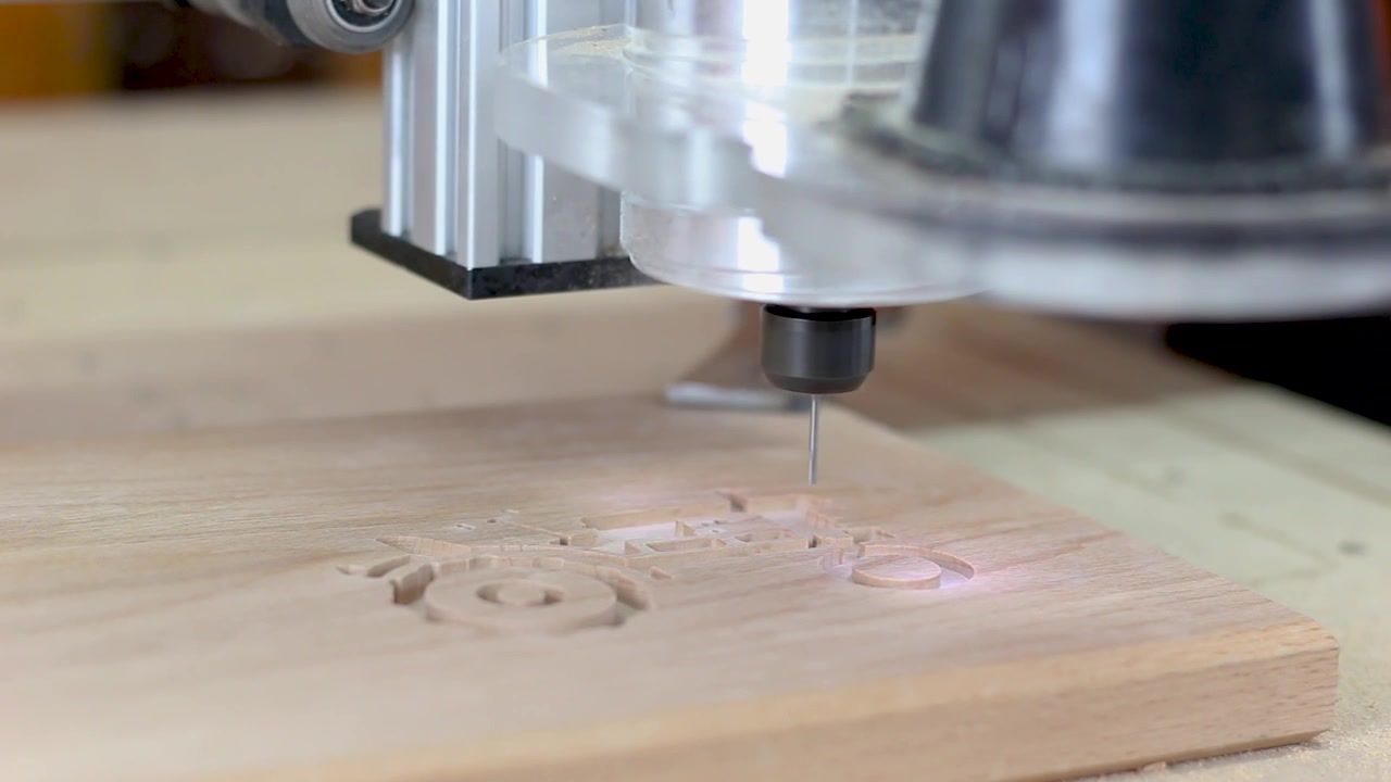 Macchina CNC intaglia un trattore nel legno di faggio. Illuminazione ad alta chiave, profondità di campo ridotta.