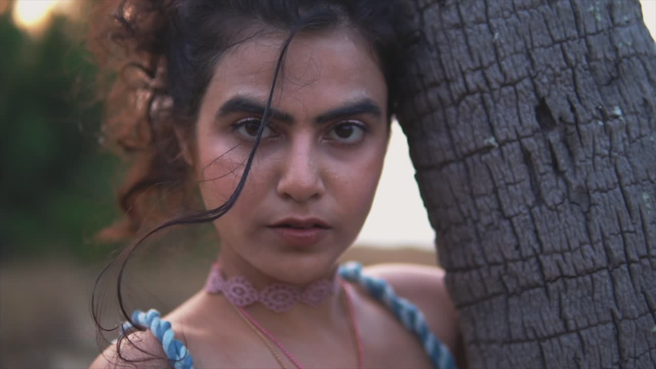 retrato de una mujer poderosa de aspecto serio descansando su cabeza en un árbol