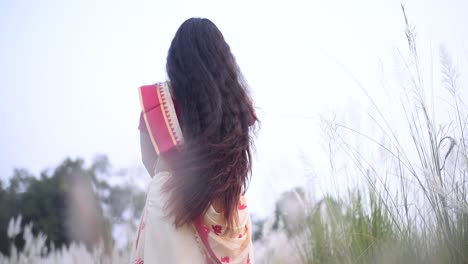 Una-Mujer-India-Vestida-De-Sari-Con-Un-Hermoso-Cabello-Largo-Y-Rizado-Se-Balancea-Y-Mueve-Su-Cabello-En-Un-Campo,-En-Cámara-Lenta