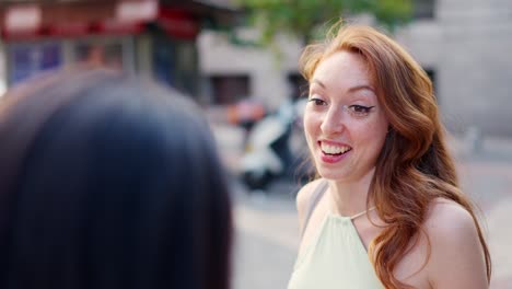 smiling red-haired woman talking in an urban setting