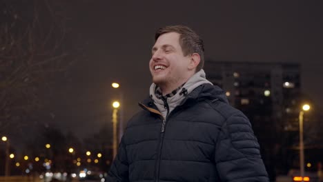 positive young man smiles and walks around preparing for an interview, cold evening in city