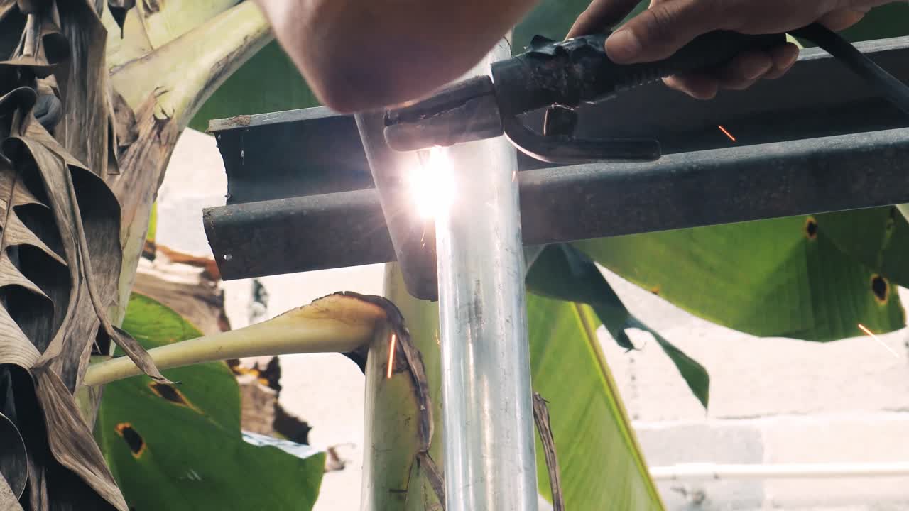 soldador profesional que emplea una máquina de soldadura industrial para unir dos piezas de metal creando una estructura metálica como parte de su trabajo diario en una pequeña empresa local