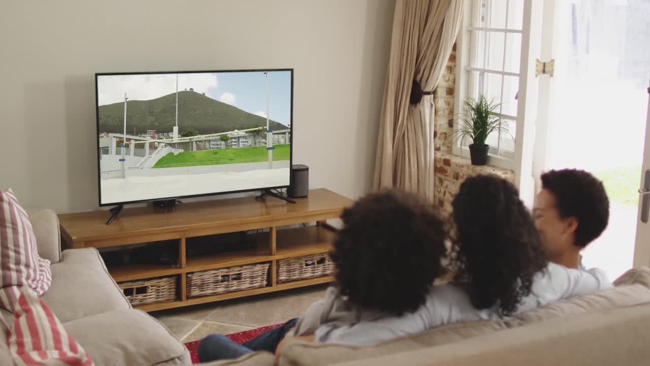 Famiglia felice seduta a casa insieme che guarda l'atletica salto in alto in TV