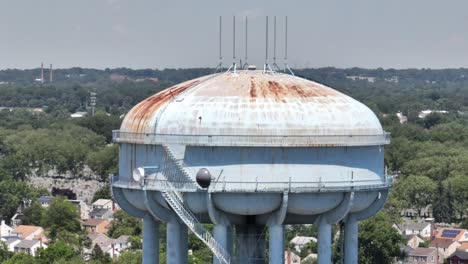 an aerial view of a light blue water tower, rusted from old age and weather