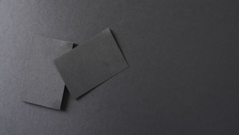 overhead view of blank black business cards on black background, copy space, slow motion