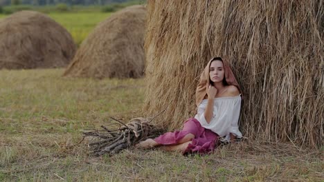 woman in a field by a haystack