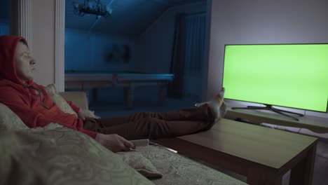 man sits on the couch at night and watches tv, chroma key