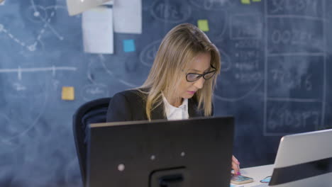 mujer de negocios caucásica trabajando en una computadora portátil mientras comprueba datos