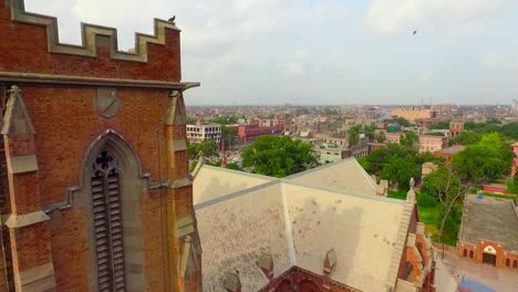 aerial flight over the beautiful old church, crossing the flag and minarets of the church, a view of city and a busy road with metro bus station and fly over