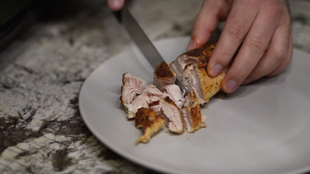 Tagliare pollo cotto al forno su un piatto vuoto in pezzi più piccoli a casa.