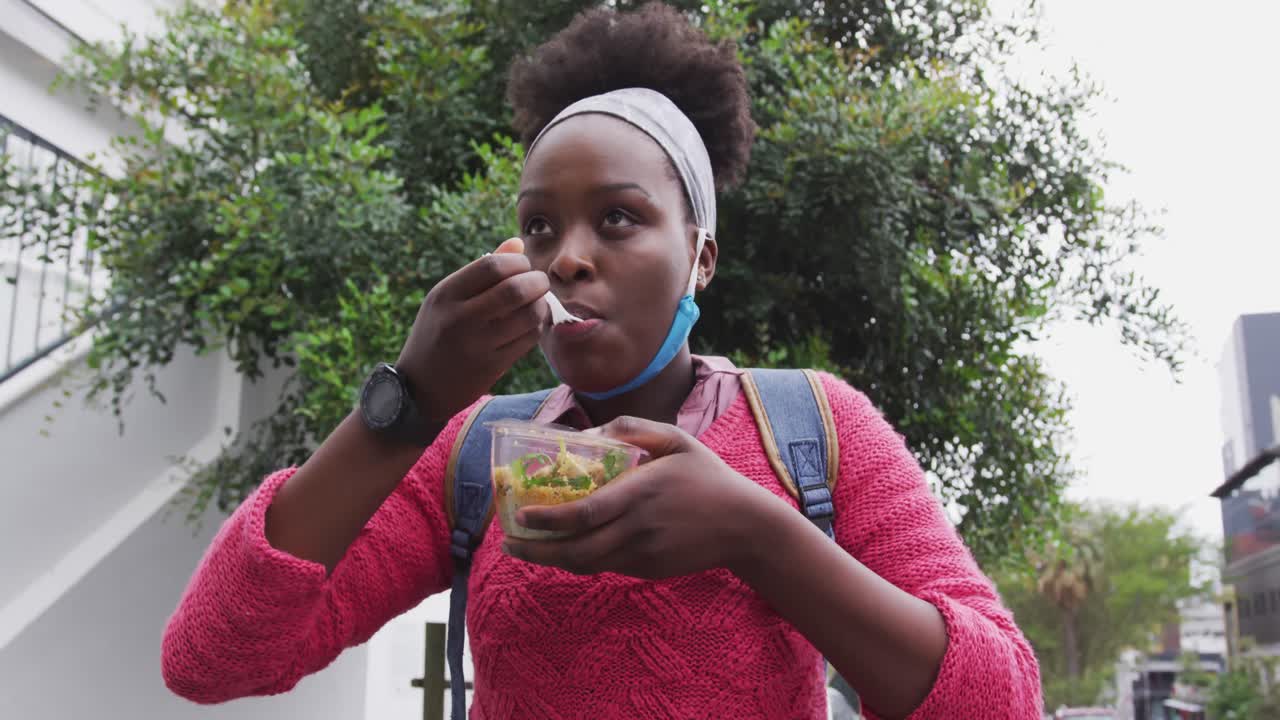 African american eating a salad in street