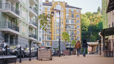 Jouful-couple-walking-street-modern-buildings-rear-view.-Happy-young-girl-dance