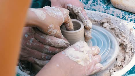 potter's hands work with clay on a potter's wheel