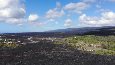 kalapana community viewed from above with lava fields and volcano in the background, hawaii island