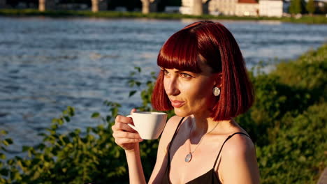 woman enjoying coffee by the riverside at sunset