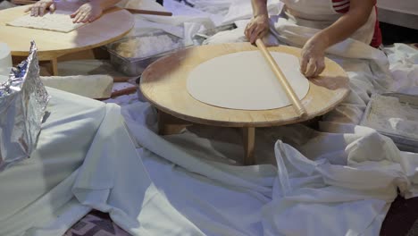 close-up of a female chef rolling out dough for a traditional gozleme dish.