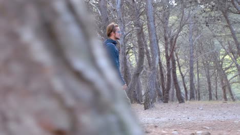 Slow-motion-shot-of-a-male-hiker-walking-through-the-forest-with-trees-passing