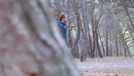 disparo en cámara lenta de un excursionista masculino caminando por el bosque con árboles pasando