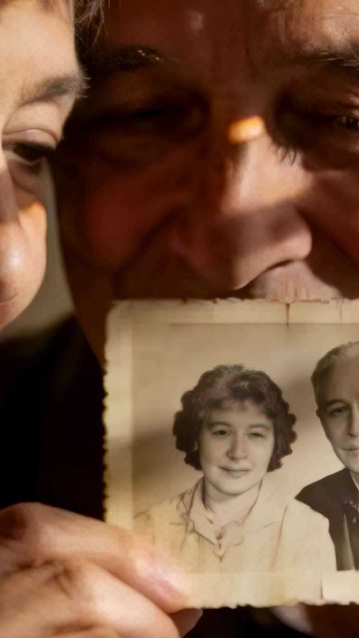 Vertical video: Presenting seniors leaning in at home, viewing portrait, hands, collar, reminiscing