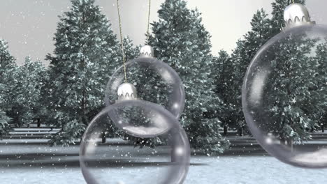 animation of christmas baubles dangling over snow falling and trees in winter scenery
