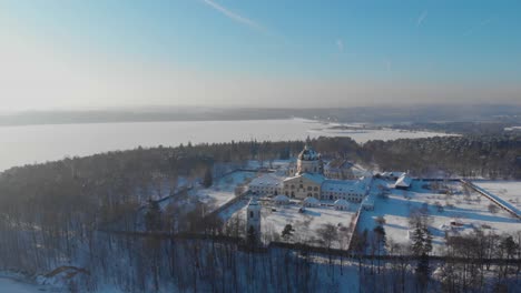 Aerial-view-of-the-Pazaislis-monastery-and-the-Church-of-the-Visitation-in-Kaunas,-Lithuania-in-winter,-snowy-landscape,-Italian-Baroque-architecture,-flying-around-the-monastery,-far-away-from-it