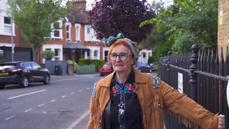 A-modern-attractive-pensioner-standing-in-a-local-street-smiling-and-thinking