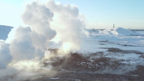 Steam-rises-from-volcanic-field-with-Reykjanes-lighthouse-in-background