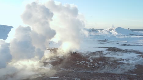 steam rises from volcanic field with reykjanes lighthouse in background