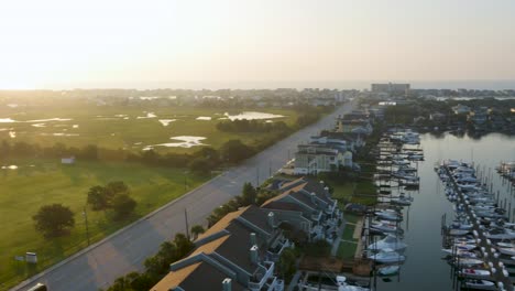 Vista-Giratoria-De-4k-Del-Puerto-Deportivo-Para-Revelar-El-Parque-Con-Hierba-Verde-Cerca-Del-Océano-Al-Amanecer