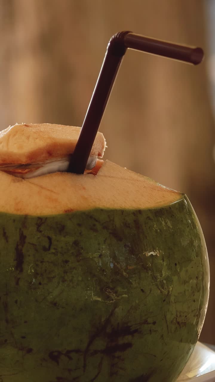 A coconut with a straw on a sunny day