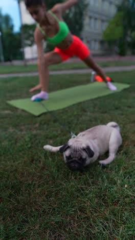 woman practicing yoga in the park with her dog