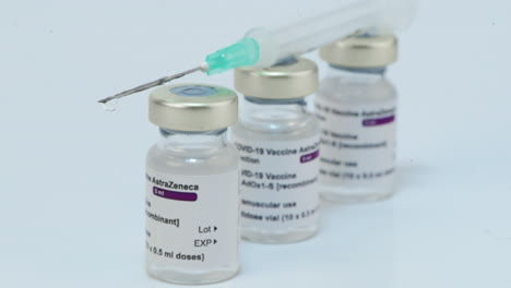 syringe with needle over astrazeneca covid-19 vaccine ampoules