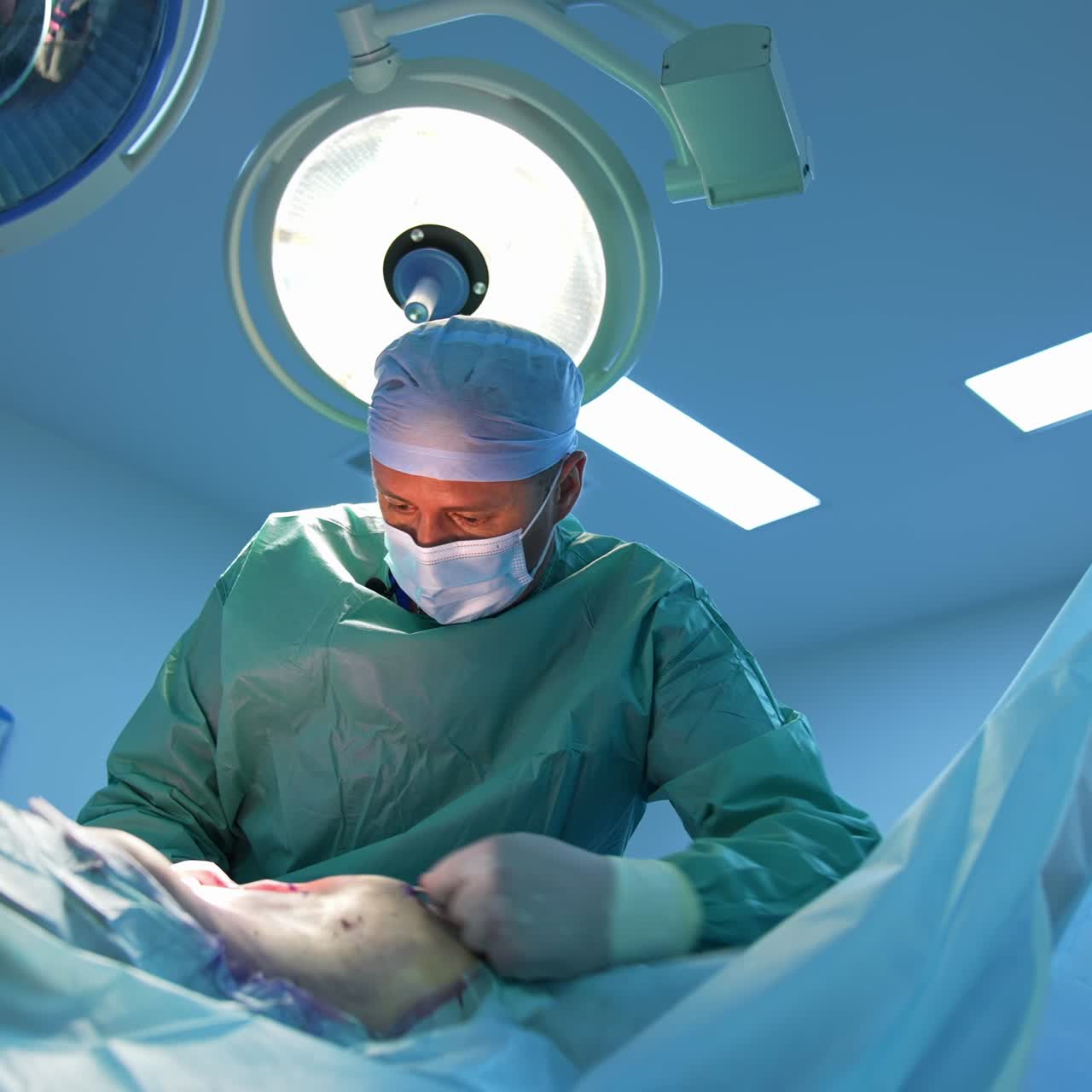 Professional surgeon doing plastic operation. Doctor in medical mask and uniform performing a surgery in the hospital. Medicine concept