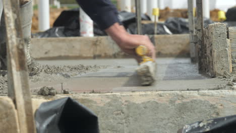 slow motion contract worker smoothing out new wet cement on slab