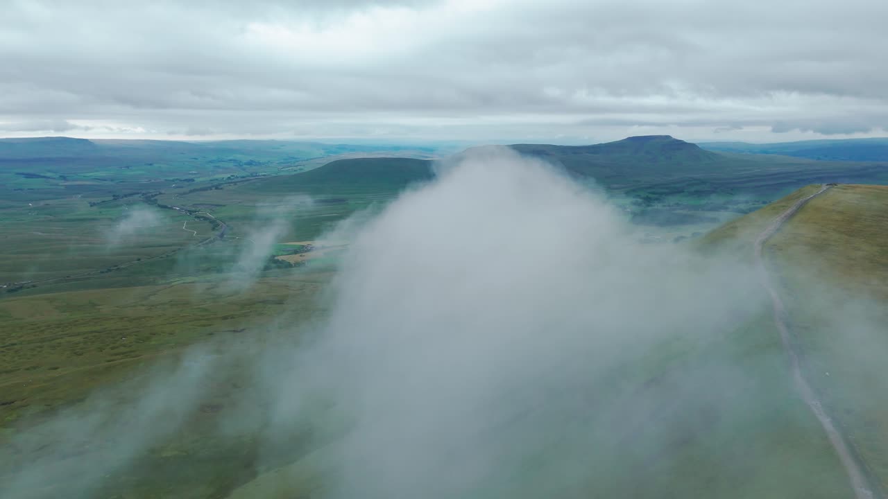 Aerial view of a vast mountain landscape with clouds and green hills