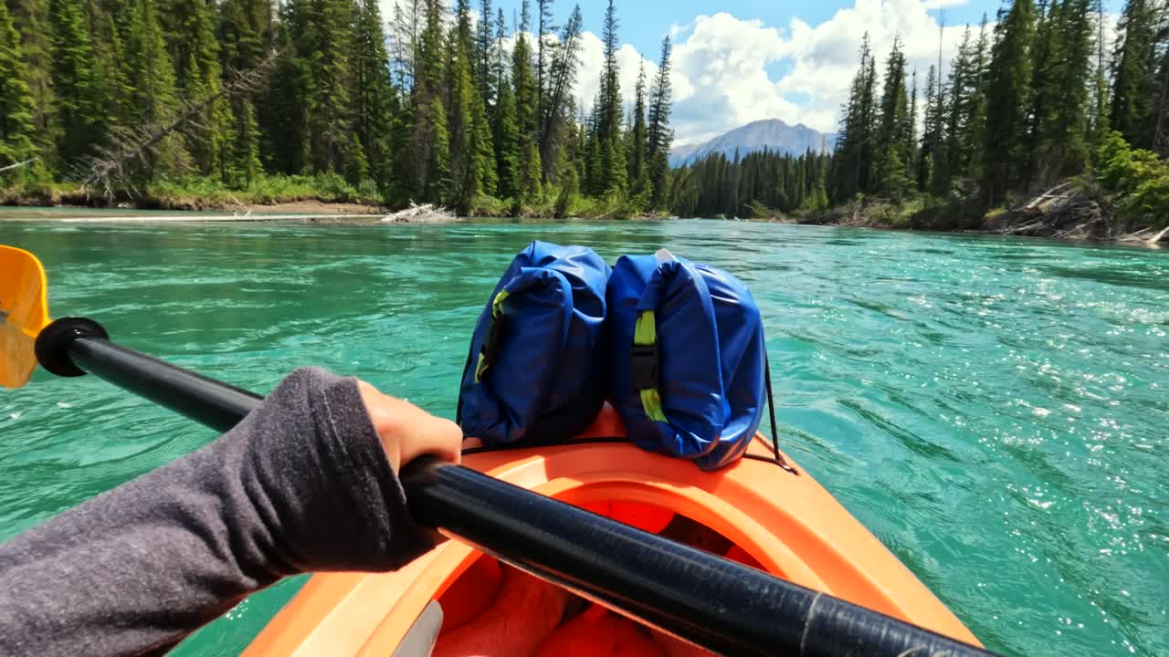 POV 4K action cam captures a kayaker paddling gently downstream on the Bow River. Surrounded by serene emerald waters and dense forest, they favour the quiet beauty of the Canadian wilderness.