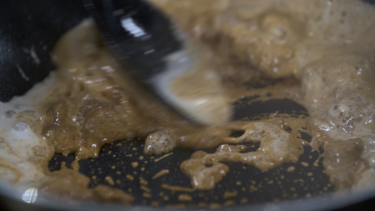 Mixing Dark Massaman Curry Paste with Fresh Coconut Milk in Non Stick Pan - Close Up