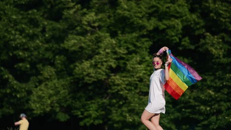 woman holding a rainbow flag in a park