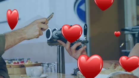 multiple red heart icons falling against mid section of man making a payment from his smartphone